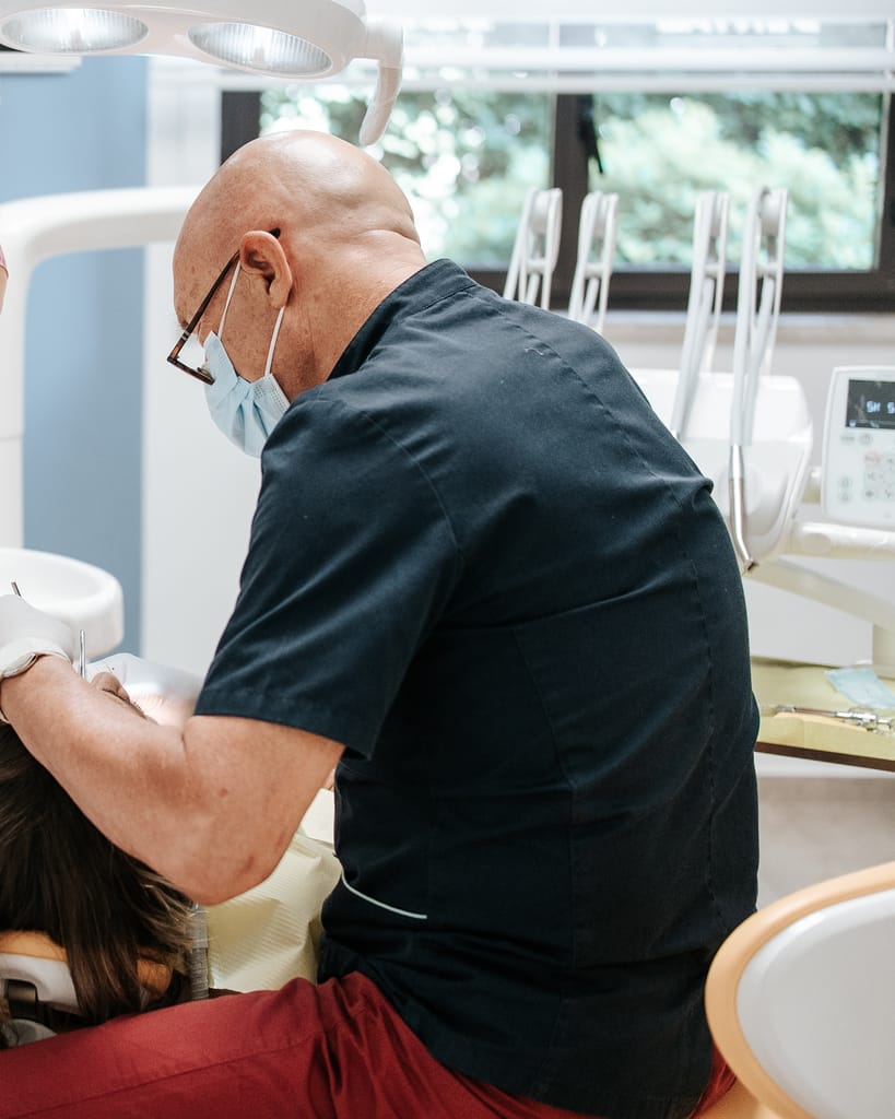 Il Dott. Ignazio D'Anna chino su una paziente adulta distesa sul riunito, TCL Dental