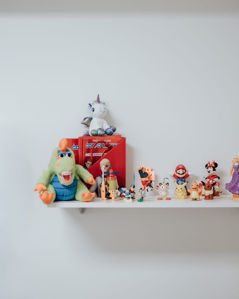 Mensola con peluche e personaggi giocattolo allineati sulla parete della sala pedodontica di TCL Dental