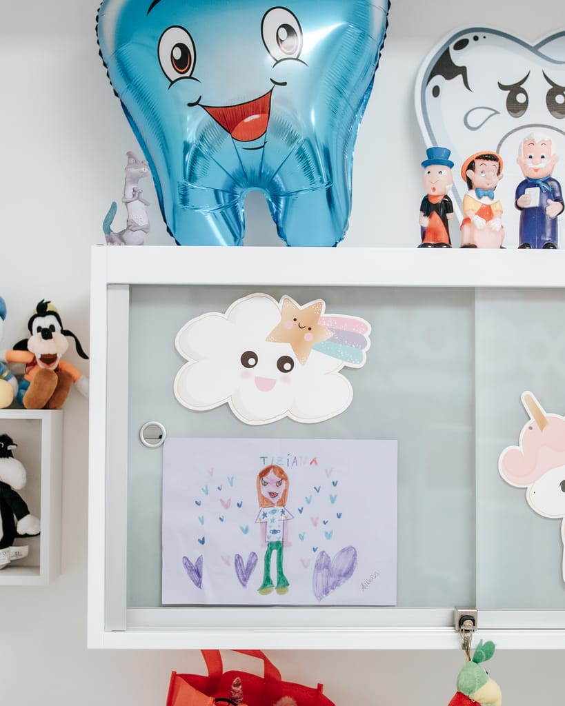 Palloncino azzurro a forma di dente sorridente e disegni colorati dei bambini appesi in bacheca, TCL Dental