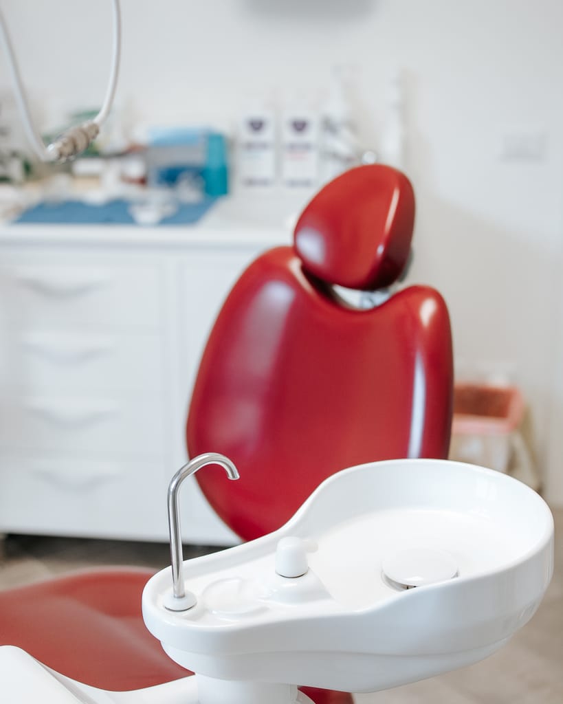 Dettaglio della poltrona rossa del riunito con la sputacchiera bianca, sala di TCL Dental