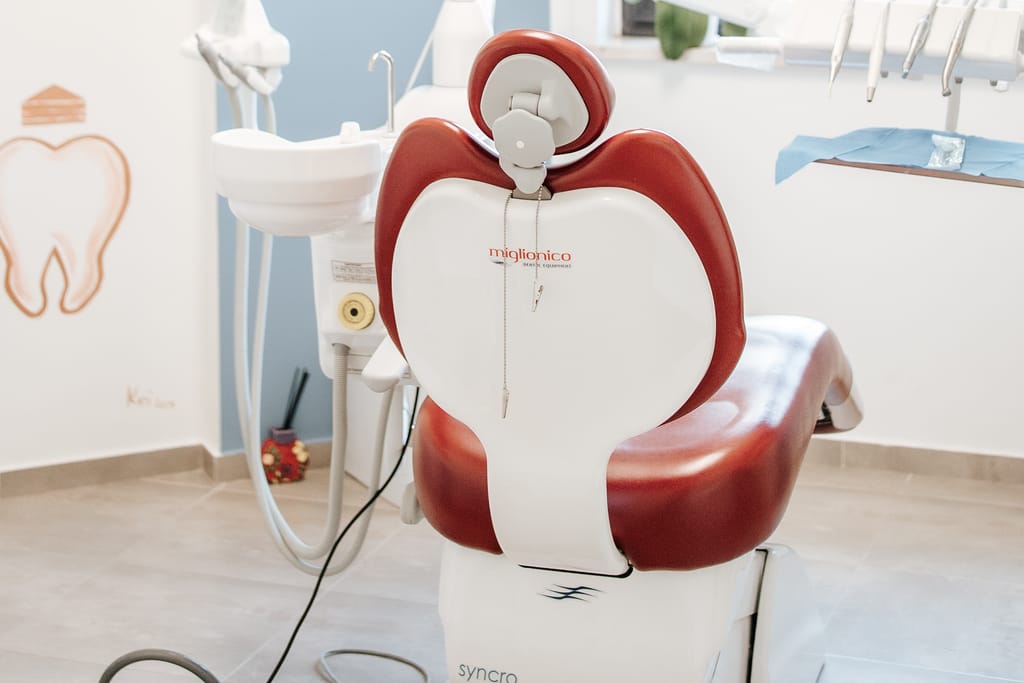 Riunito con poltrona rossa e parete azzurra decorata con illustrazioni di denti, sala di TCL Dental