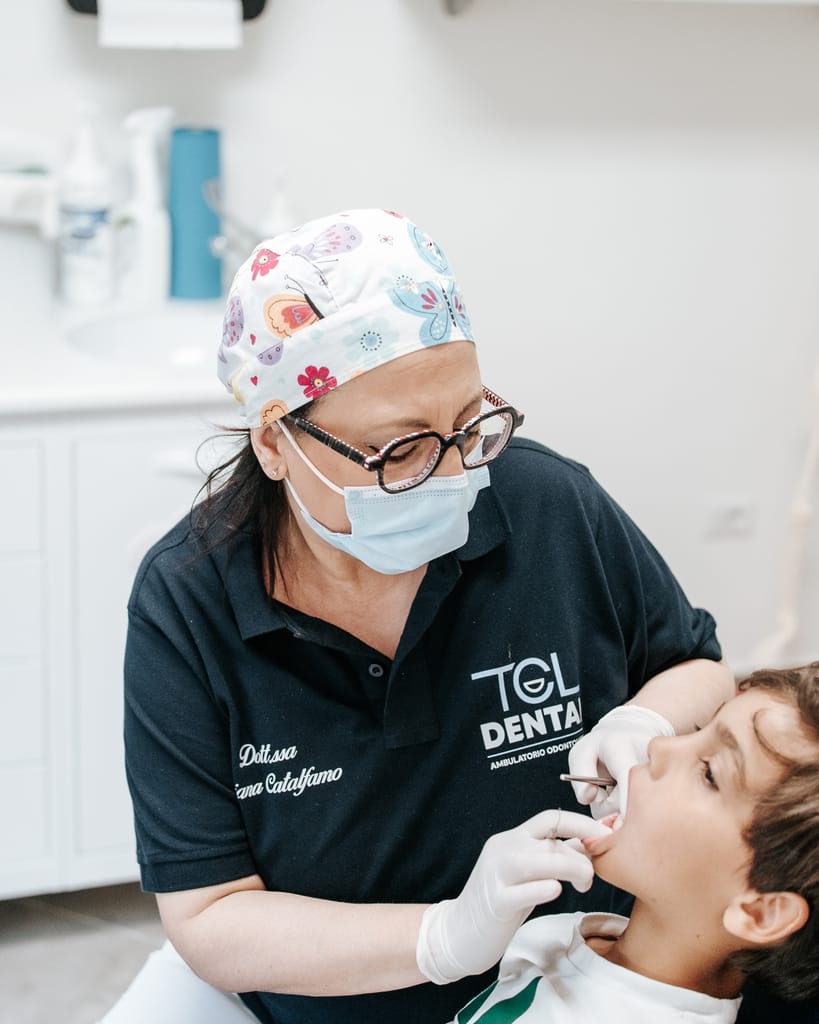 La Dott.ssa Tiziana Catalfamo, con la polo TCL Dental, visita un bambino disteso sul riunito